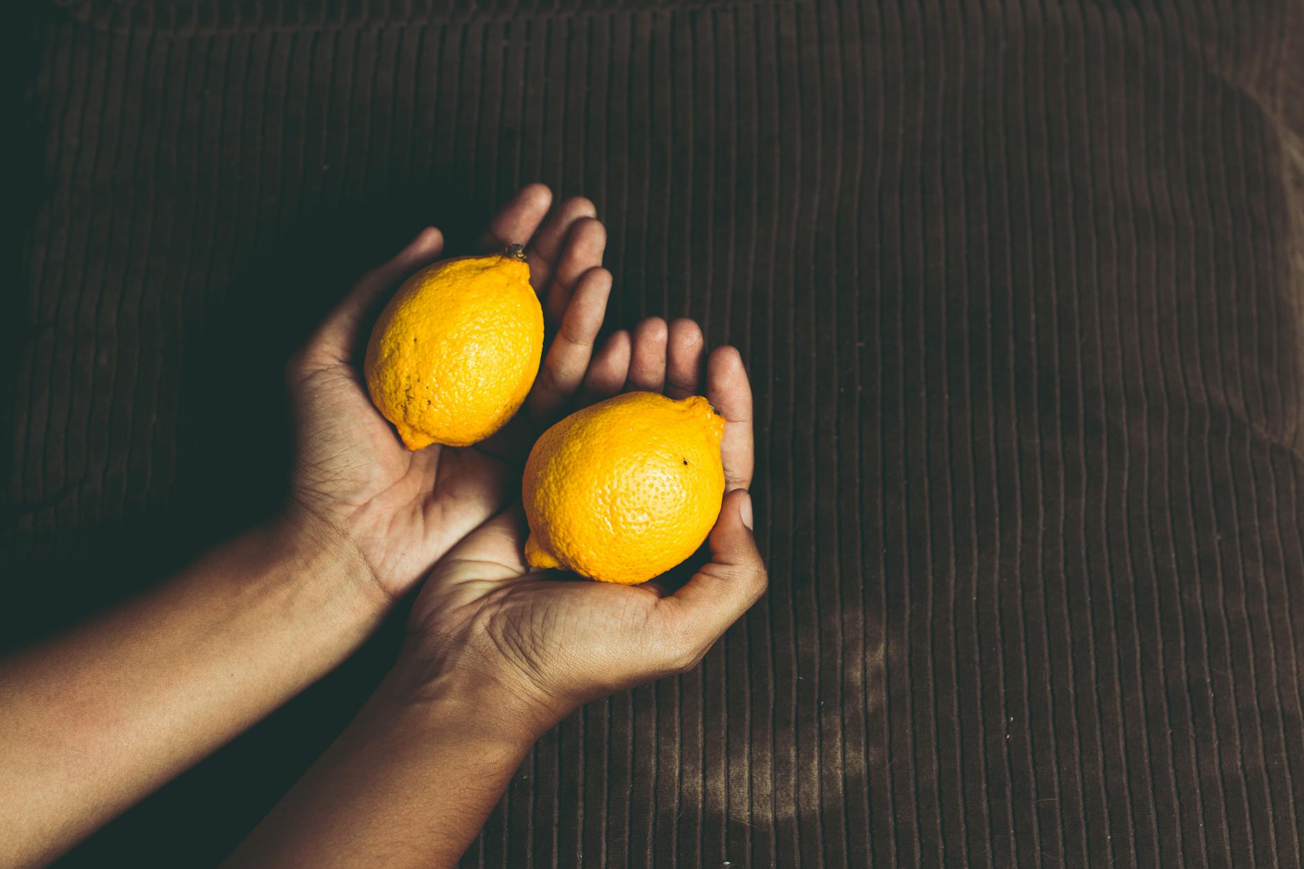 Hands holding fresh lemons, symbolizing natural vitality and renewed pleasure